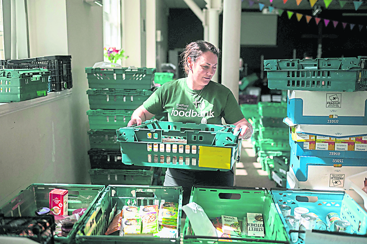英国布拉德福德中央食物银行的志愿者们正忙着将食物打包，准备派发给需要的人士。（图：法新社）(photo:SinChew)
