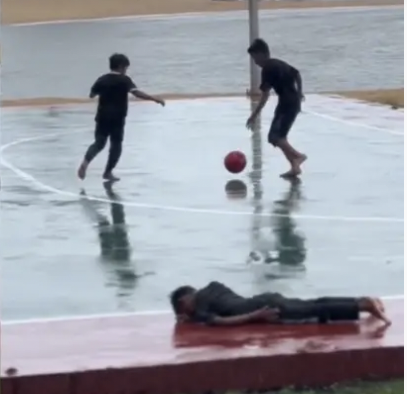 少年雨中踢球滑倒受伤 球友抬场边继续踢球
