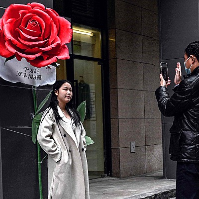 A couple takes photos next to an installation of roses outside a shopping mall in Beijing, China, on Valentine's Day. AFP