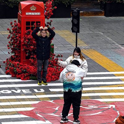 People take photos next to an installation of roses outside a shopping mall in Beijing, China, on Valentine's Day. AFP