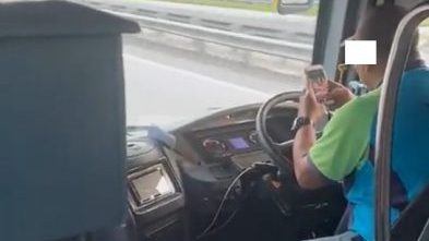 双臂托方向盘 长巴司机边驾驶边玩手机