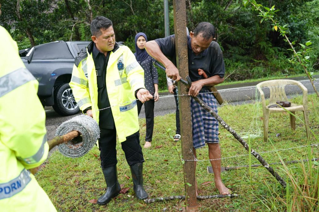 东：警民同心，登州总警长及警员协助村民装置铁丝篱笆，防止村民饲养的水牛在水灾灾区游荡。
