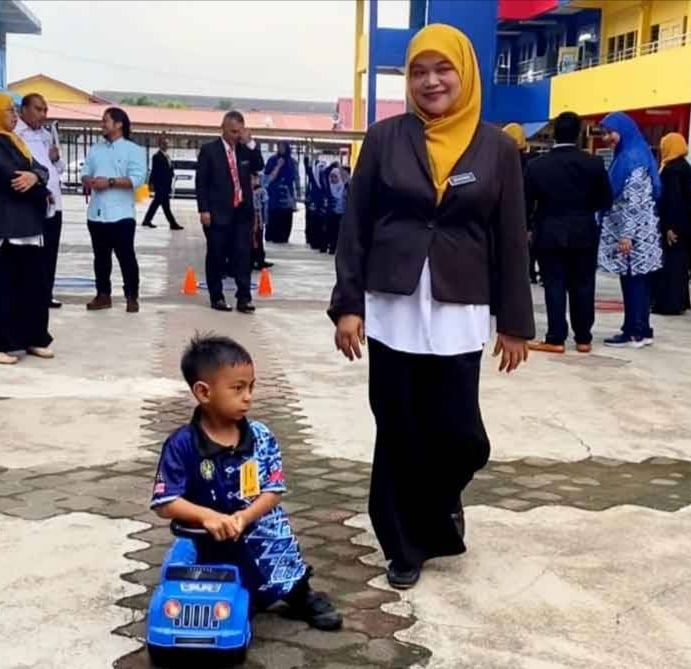 来自丹州哥打峇鲁的7岁男童阿都哈金天生患有脑瘫疾病，先天性行动不便，第一天上学以玩具车代步。